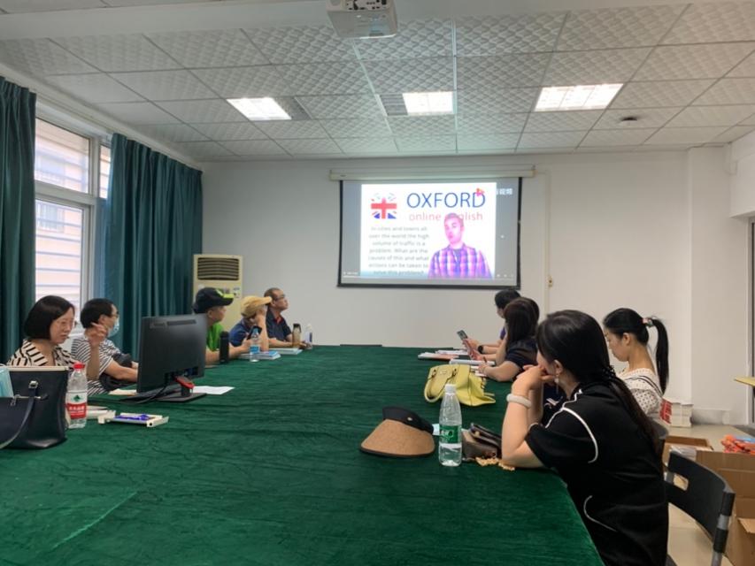 A group of people sitting at a table watching a presentationDescription automatically generated with low confidence